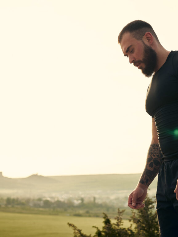 Sporty man standing on hill road in the countryside