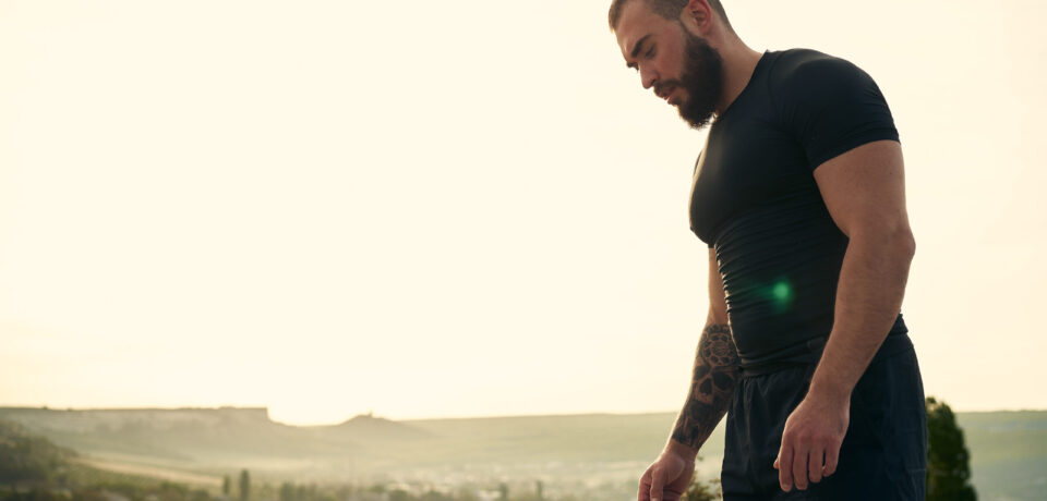 Sporty man standing on hill road in the countryside